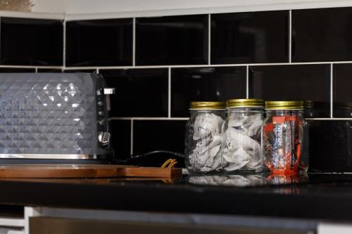 three glass jars sitting on a counter next to a microwave at Cute Duplex Apartment in Leeds in Kirkstall
