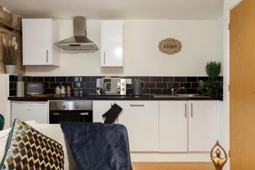 cocina con armarios blancos y microondas en Cute Duplex Apartment in Leeds en Kirkstall