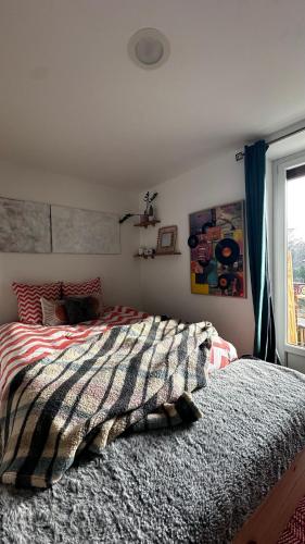 a bedroom with a bed with a striped comforter and a window at Chez Marie en Savoie in La Ravoire