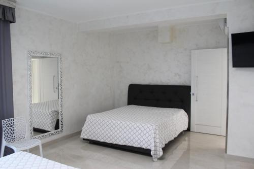 a bedroom with a bed and a mirror and a chair at Hotel Presidente in Porto Cesareo
