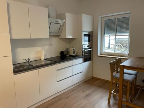 a kitchen with white cabinets and a table and a window at "be-together" Engabrunn in Engabrunn