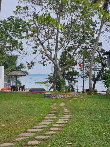 a stone path in the grass with a tree in the background at Lake facing Villa-Water sport activities-Niva Waterways in Vaikom