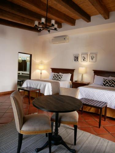 1 Schlafzimmer mit 2 Betten, einem Tisch und Stühlen in der Unterkunft Hotel El Farol in Parras de la Fuente