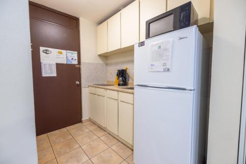een keuken met een witte koelkast en een bruine deur bij Golden Dreams Studio 306 B in Isabela