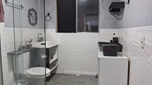 a bathroom with a toilet and a glass shower at Loft Vista de Vila Velha in Vila Velha