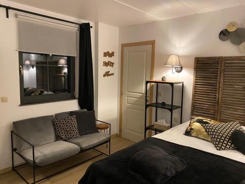 1 dormitorio con cama, sofá y ventana en Le petit studio de l'espace bien être, en Libin