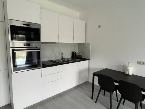 een keuken met witte kasten en een zwarte tafel en stoelen bij Appartement Brussels Airport 2 in Machelen