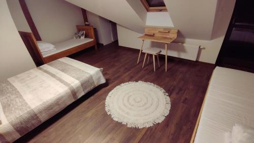 a bedroom with a bed and a table and a rug at Chwile w Starym Sączu, sauna i beczka in Stary Sącz