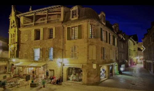 a large brick building on a city street at night at Appartement de prestige avec parking Sarlat centre in Sarlat-la-Canéda