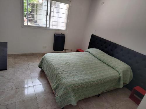 een slaapkamer met een bed met een groene deken en een raam bij Departamento W R T 1 in Villa Carlos Paz