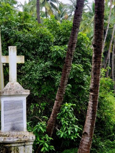 a cross on top of a monument in front of trees at The Bungalow Bogmalo An 1880 Indo Portuguese Heritage Beach Villa South Goa in Bogmolo