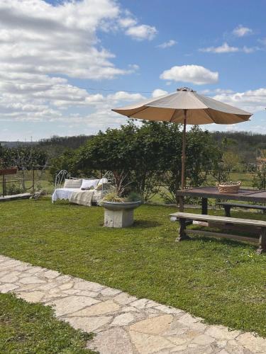 - une table de pique-nique avec un parasol à côté d'un banc dans l'établissement La demeure des poètes gîtes, à Les Cabannes