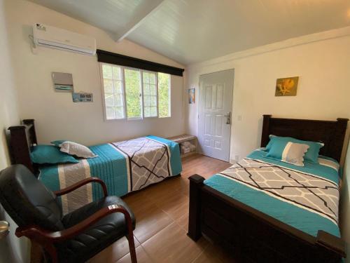 ein Schlafzimmer mit 2 Betten und einem Stuhl darin in der Unterkunft Aeolus Guest House in José Pobre