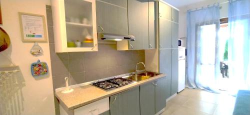 una cocina con fregadero y estufa horno superior en Villa Acquamarina Villasimius, en Villasimius