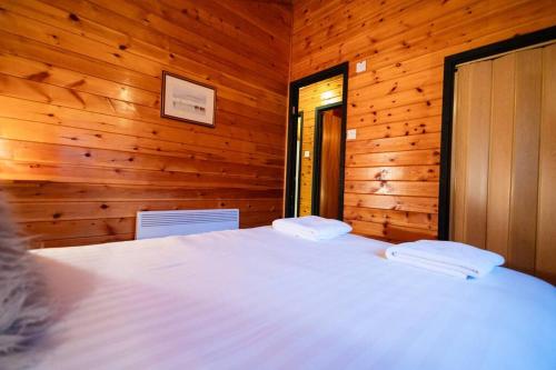 a bedroom with a white bed in a wooden room at Cozy Norwegian Style Log Cabin in Rural Snowdonia - 2 Bedrooms & Parking by Seren Short Stays in Ffestiniog