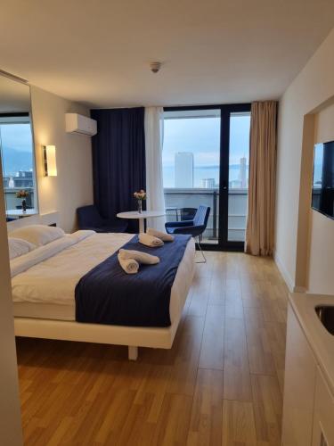 a hotel room with a bed and a table and windows at PANORAMA ORBICITY in Batumi
