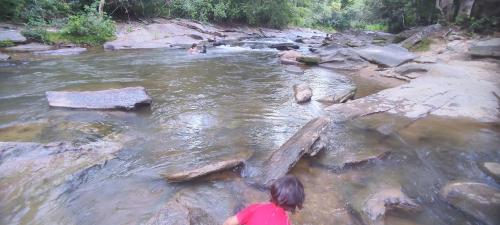 a woman is standing in a river with rocks at Pousada Simples Assim in Pirenópolis