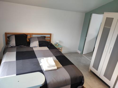 een slaapkamer met een bed met een geruite deken bij Passage d'Élise in Saint-Ségal