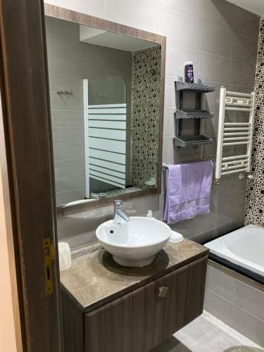 a bathroom with a sink and a tub and a mirror at Résidence palmerie in El Haouach