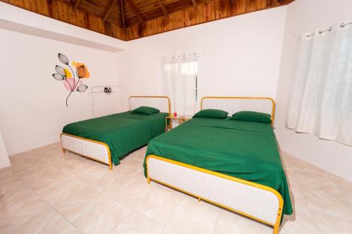2 łóżka z zieloną pościelą w białym pokoju w obiekcie Bell Air Seaview (3 BDRM 3 BATH) w mieście Runaway Bay