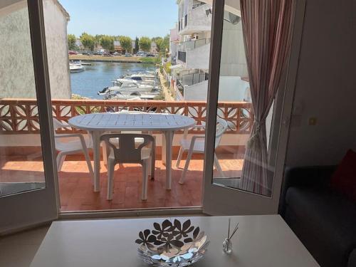 um quarto com uma mesa e uma varanda com barcos em Lindo apartamento con vistas al puerto Mistral em Empuriabrava