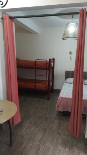 1 dormitorio con 2 camas, cortinas rojas y mesa en Ronald, en Piriápolis
