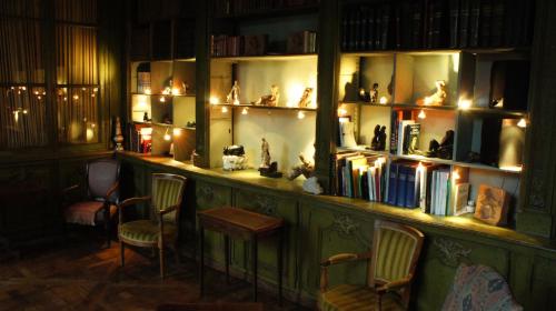 a room with a shelf filled with books and chairs at Hôtel particulier Maleteste in Dijon