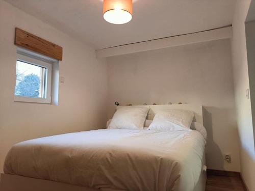 um quarto com uma grande cama branca e uma janela em Chalet au bord du lac em Aydat
