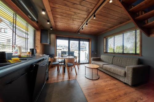 a kitchen and living room with a couch and a table at Domki 1010 m in Ząb