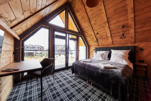 a bedroom with a bed and a desk and a window at Domki 1010 m in Ząb