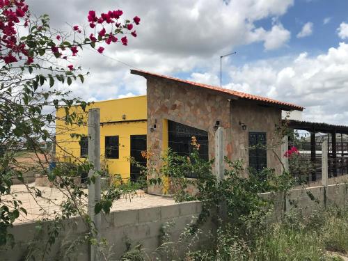 a yellow building with a fence in front of it at Entre Serras Gastropub e Chalés in Monte das Gameleiras