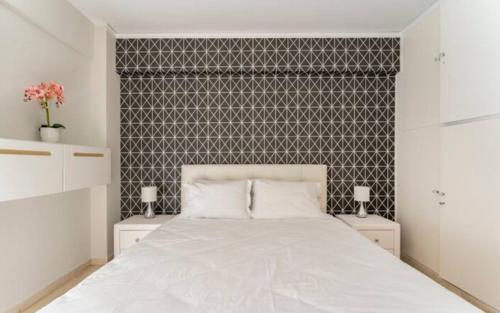 a bedroom with a white bed and a wall at Seaside Beauty 5 min Vouliagmeni Beach in Athens