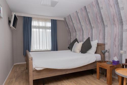 a bedroom with a large bed and a window at Zeeuwse Zot in Wissenkerke