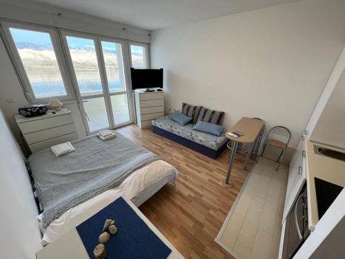 a small bedroom with a bed and a couch at Sea view & pool studio by Pag tours in Pag