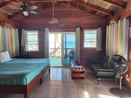 um quarto com uma cama, uma ventoinha e um sofá em Coco's Beachfront Cabanas em Seine Bight Village