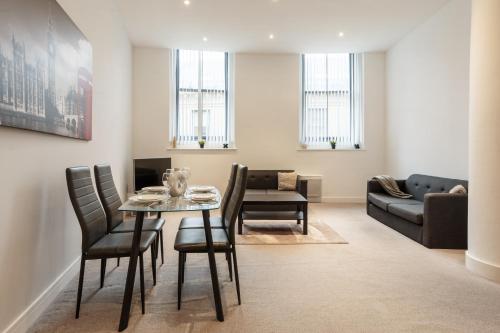 a living room with a table and chairs and a couch at Smart Living Apartments - One Beds in Bradford