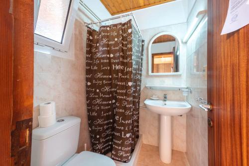 a bathroom with a sink and a toilet and a shower curtain at Mimosa Apartments with Pool in Paleokastritsa