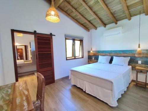 1 dormitorio con cama blanca y mesa en Casablue Baiana, en Porto Seguro