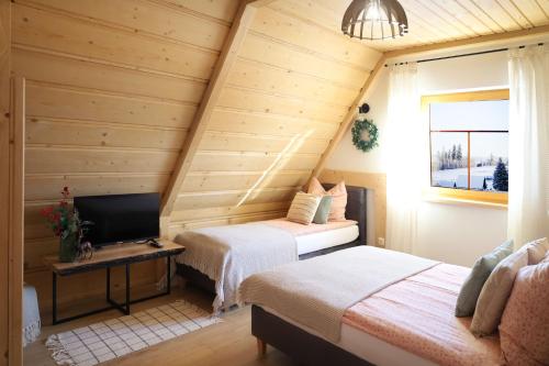 a room with two beds and a television in a attic at Apartamenty Za Wierchem in Bańska Wyżna