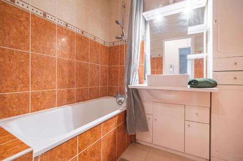 une salle de bain avec une baignoire et un lavabo dans l'établissement Joli appartement Le Chalet + parking, à Reims
