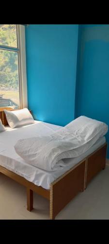 Bett in einem Zimmer mit blauer Wand in der Unterkunft Rishikesh Prithvi yatra hotel and kedarnath in Rishikesh