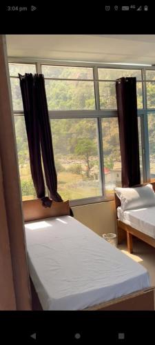 1 Schlafzimmer mit 2 Betten und einem Fenster in der Unterkunft Rishikesh Prithvi yatra hotel and kedarnath in Rishikesh