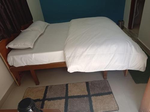 Bett mit weißer Bettwäsche und Kissen in einem Zimmer in der Unterkunft Rishikesh Prithvi yatra hotel and kedarnath in Rishikesh