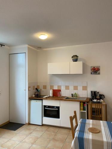 une cuisine avec des armoires blanches et une table avec une table dans l'établissement Soulac Studio Jo Centre et Plage, à Soulac-sur-Mer