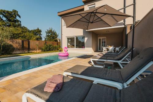 a swimming pool with lounge chairs and an umbrella at VILLA JADRANKA in Krnica