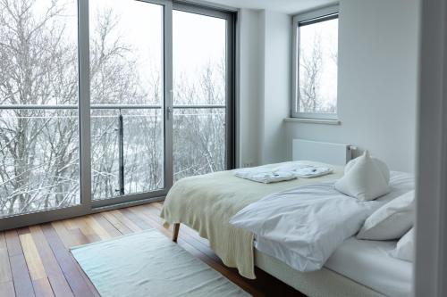 biała sypialnia z łóżkiem i dużymi oknami w obiekcie Boutique Penthouse w Wilnie