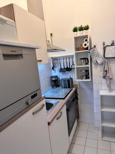 Hansestübchen في فيسمار: مطبخ صغير فيه أجهزة بيضاء وبلاط أبيض