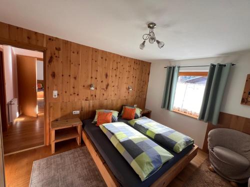 1 dormitorio con 1 cama y 1 silla en Ferienwohnungen Unterfeld en Alpbach