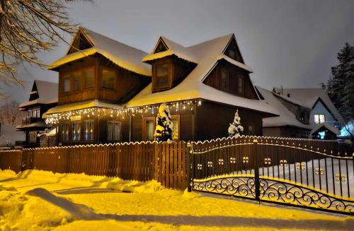 ein Haus mit Weihnachtslichtern vor einem Zaun in der Unterkunft Pod Śnieżynką in Zakopane