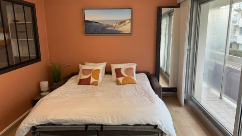 una camera da letto con un letto con pareti arancioni e una finestra di Chez Tonton, Studio cabine au calme avec parking a Le Touquet-Paris-Plage